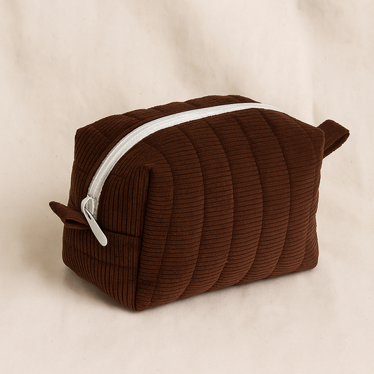 Brown ribbed toiletry bag with a white zipper on a beige background