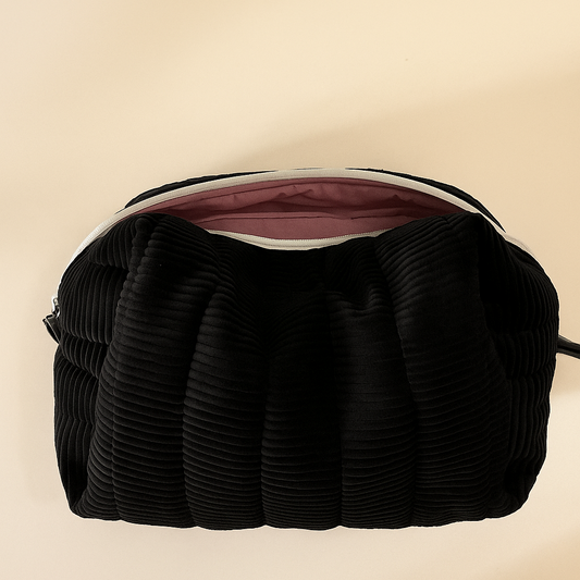Black textured cosmetic bag on a beige background